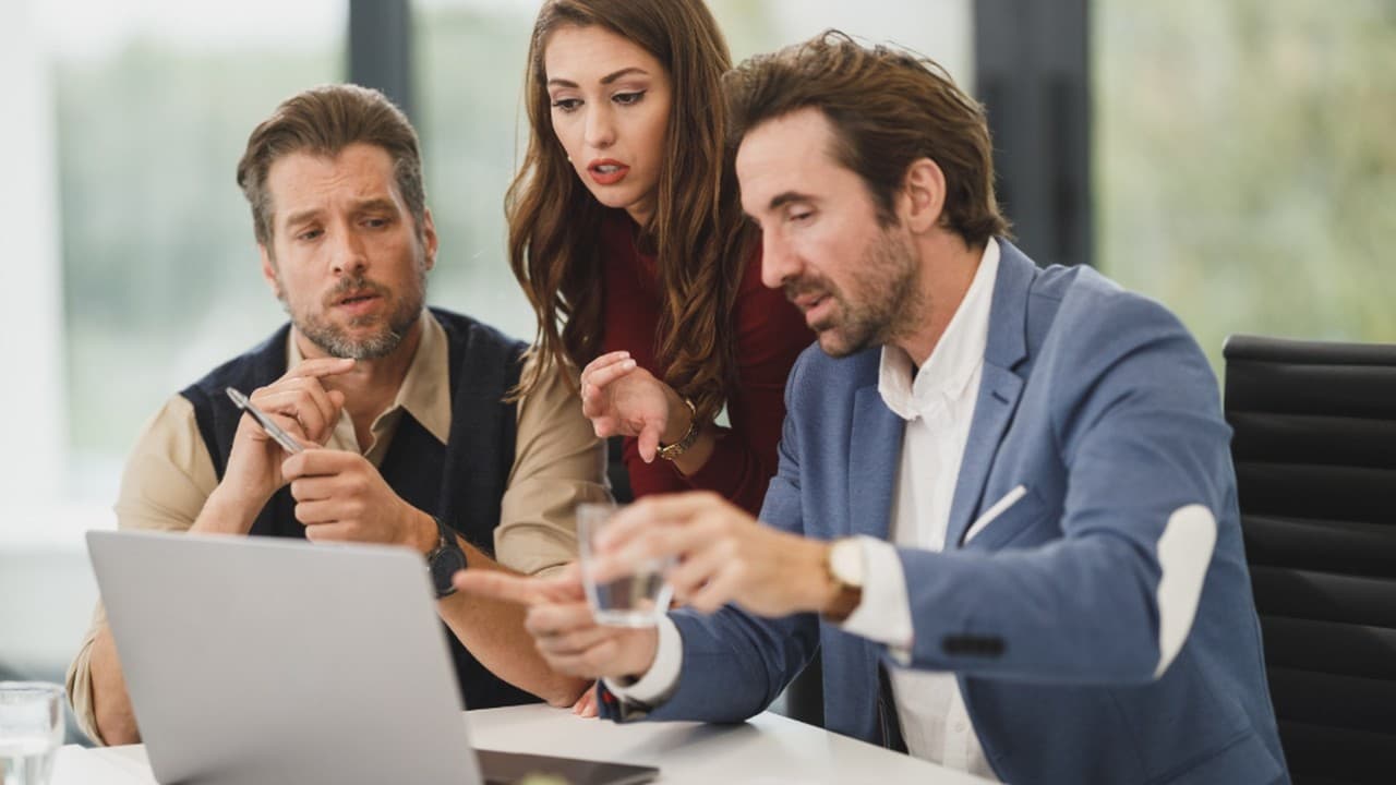 Three colleagues discussing something on a laptop